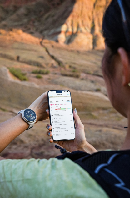 A person outdoors checking the Suunto app on a phone while wearing a Suunto watch